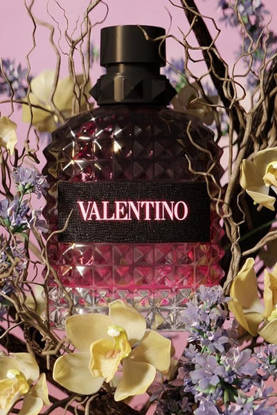Valentino perfume bottle surrounded by flowers on a pink background